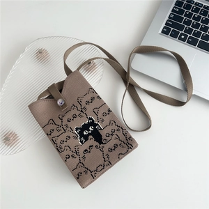Detail of a brown knitted crossbody phone bag featuring a cute cat jacquard pattern and strap