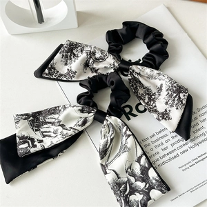 Close-up of satin scrunchies with long ribbons and black vintage landscape print