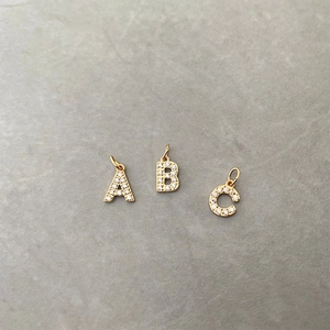Macro shot of gold-plated A, B, C letter charms with micro-paved sparkling zircons