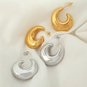 Minimalist 18K gold and silver hollow C-shaped hoop earrings on silk background