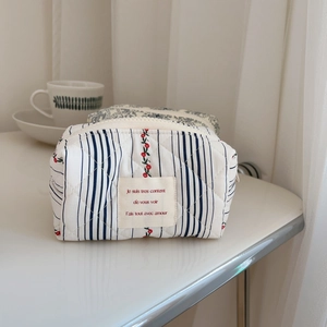 Detail of quilted cotton floral makeup bag with blue stripes and cherry patterns