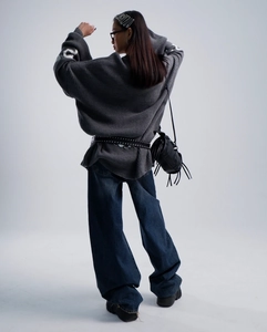 Oversized jacquard sweater with wide-leg jeans and fringe crossbody bag seen from back