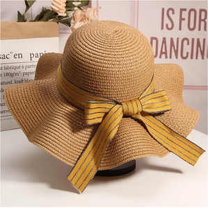 Close-up of a wide-brim straw hat with a yellow and black striped bow for beach vacation