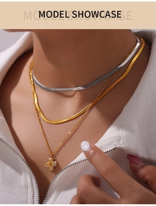 Close-up of layered gold and silver snake chains with a filigree clover pendant on model