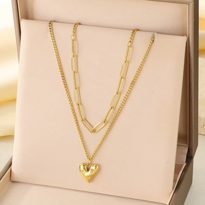 Gros plan du collier double rang doré avec pendentif cœur dans un écrin à bijoux