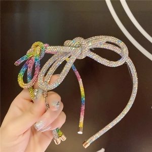 Detail of a thin headband featuring a rainbow rhinestone bow with a sparkling finish