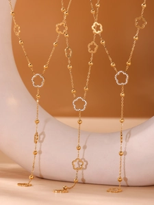 Detailed macro of gold flower necklace with zircon tassel and multi-layered steel beads