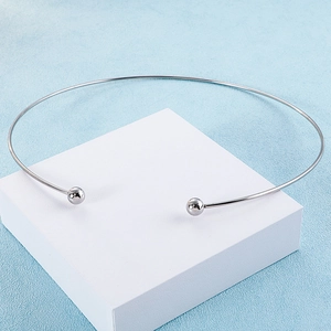 Minimalist silver C-shaped rigid torque necklace with ball ends on a white cube display