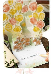 Macro shot of 3D pop-up floral greeting card featuring gold foil details and handwritten area