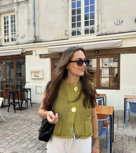 Detailed knit texture of green sleeveless cardigan with large gold buttons and front pockets