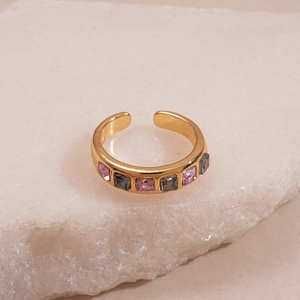 Close-up of gold geometric ring set with pink and grey square crystals on white rock