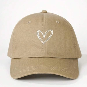 Close-up of khaki cotton baseball cap featuring white embroidered heart on the front panel