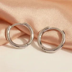 Detailed close-up of silver-toned hoop earrings on champagne satin backdrop
