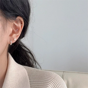 Detail showing set of S925 sterling silver pearl and diamond stud earrings on model
