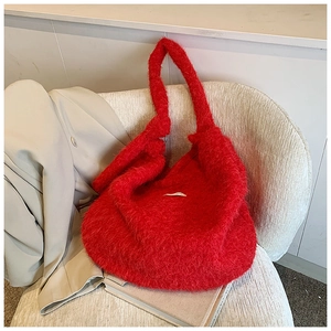 Close-up of a large red fuzzy tote bag on a beige sofa with soft fabric texture