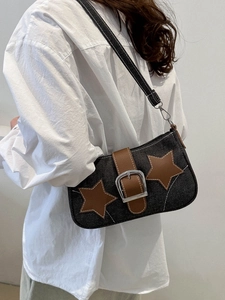 Detail of dark blue denim shoulder bag with brown leather stars and metallic buckle