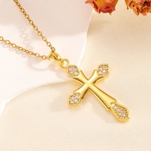 Detail einer goldenen Kreuzkette mit Zirkonia-Inlay auf strukturiertem Seidenhintergrund