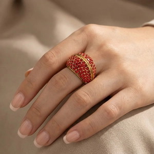 Close-up of wide gold ring set with red pave stones on a model's finger