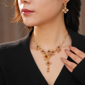 Close-up of vintage gold flower jewelry set with red gems worn by a model