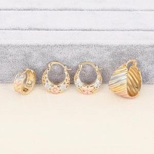Detail van vier bloem- en vlinderoorbellen in goud, zilver en roségoud ontwerp