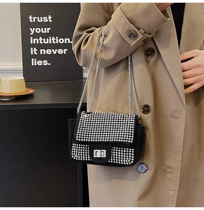 Close-up of sparkling rhinestone handbag featuring silver chain strap and metal turn-lock