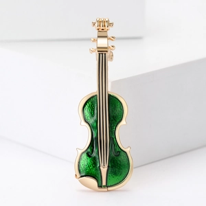 Detail of golden violin brooch with green enamel inlay on a clean geometric background