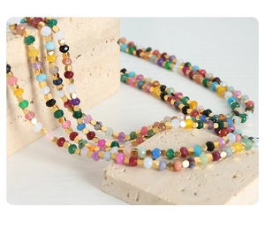Macro shot of colorful faceted tourmaline beads and golden spacers on textured stones