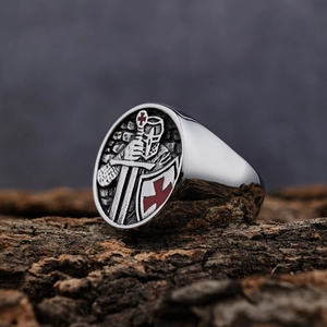 Macro shot of silver Knights Templar signet ring with red enamel cross on rustic wood