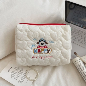Detailed close-up of a white heart-quilted puppy makeup bag with colorful embroidery