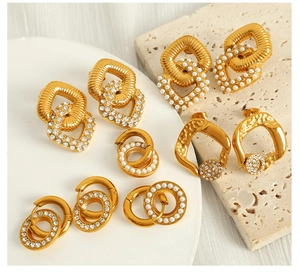Detailed view of geometric gold earrings with pearls and zircons on a marble base