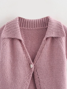 Detailed macro view of V-neck knit top showing chunky texture and single white button