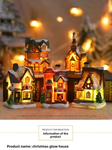 Close-up of lighted Christmas resin village houses with snowy glitter on vintage books