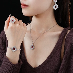 Detailed view of silver flower jewelry set with red gemstones on professional model
