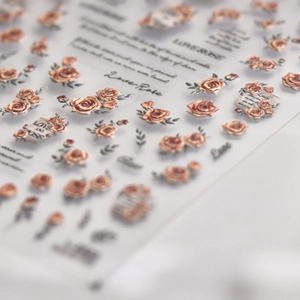 Dettaglio macro di adesivi per unghie con rose champagne a rilievo e scritta Love Rose