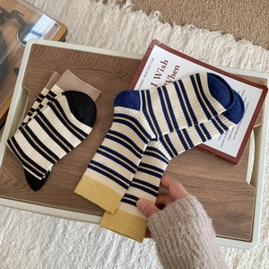 Cozy Korean style striped mid-calf socks in cotton blend on wooden tray with books