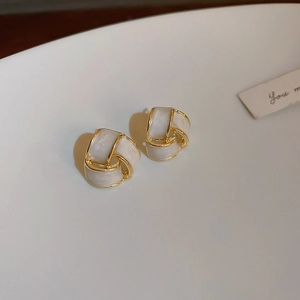 Gros plan sur les boucles d'oreilles géométriques crème avec spirale dorée