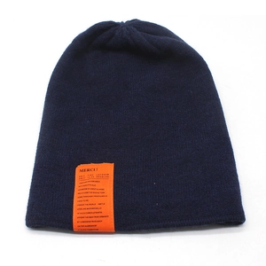 Close-up of navy knit beanie with an orange Merci label and fine woven texture detail