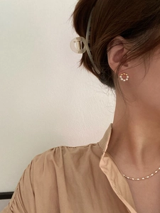 Detail of 925 silver pearl stud earrings and slim chain necklace worn by a model