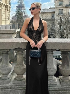 Elegant black lace halter maxi dress with backless design and satin skirt on a balcony