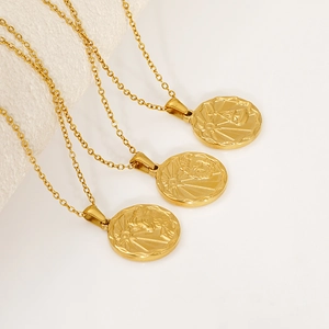 Three gold stainless steel zodiac necklaces with embossed round pendants on a textured base