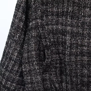 Detailed close-up of black tweed fabric texture with metallic silver threads and side pocket