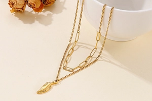 Detail of golden double-layer necklace with wing pendant and paperclip chain style