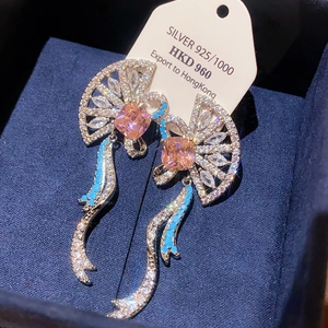 Macro view of vintage fan-shaped silver earrings with pink gemstones in a velvet box