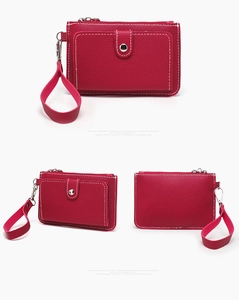 Detail view of red lychee grain leather coin purse with metal snap and wrist strap