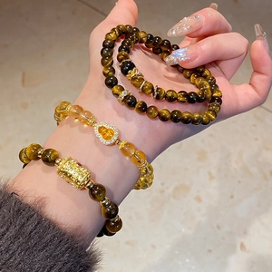 Detailed close-up of tiger eye stone and zircon flower beads on a luxury layered bracelet