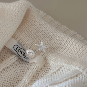 Asymmetric 925 sterling silver starfish and shell stud earrings on cream knit sweater