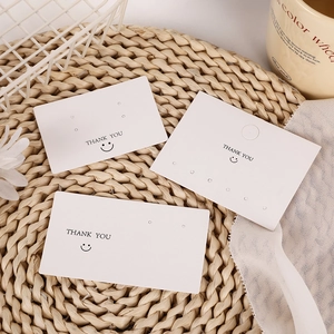 White rectangular THANK YOU jewelry cards for earrings display on a woven mat