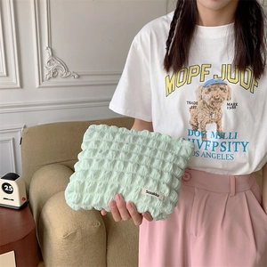 Detail of mint green cloud puff makeup bag with pleated texture and woven brand label