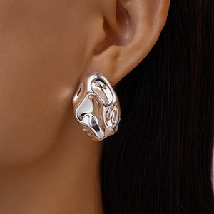 Close-up of shiny silver irregular lava texture earrings on model showing liquid metal style