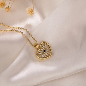 Vue détaillée du collier cœur doré avec pendentif œil maléfique et cristaux sur soie